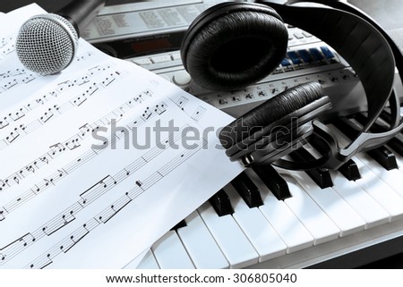 Headphones with music notes and microphone on synthesizer close up