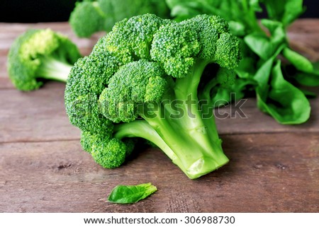 Fresh broccoli with spinach on wooden table close up