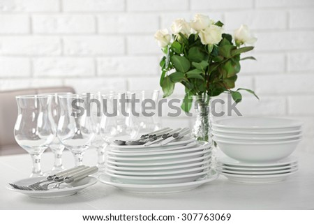 Clean plates, glasses and cutlery on white table
