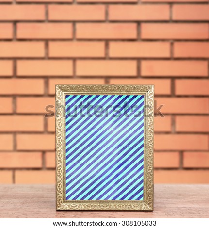Old frame with striped canvas standing on table on brick wall background