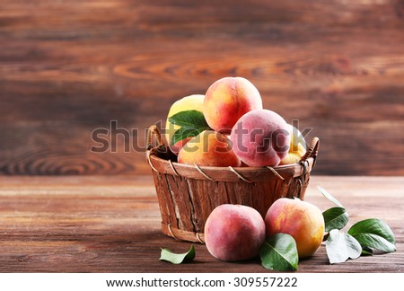 Fresh peaches in wicker basket on wooden background