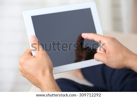 Male hand holding PC tablet on home interior background