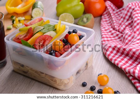 Tasty lunch in plastic containers on wooden table close up