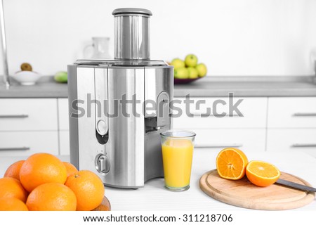 Juicer and fruits on table in kitchen, close up