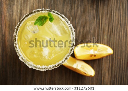 Glass of lemon juice on wooden table, top view