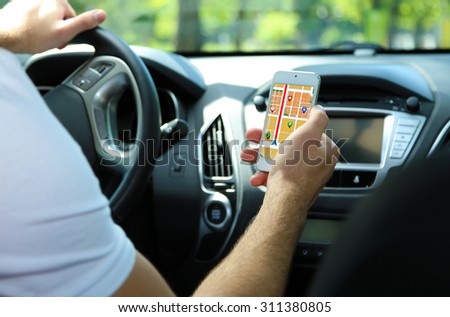 Man sitting in the car and holding smart phone with map gps navigation application