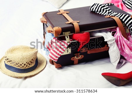 Suitcase with clothing on bed in room