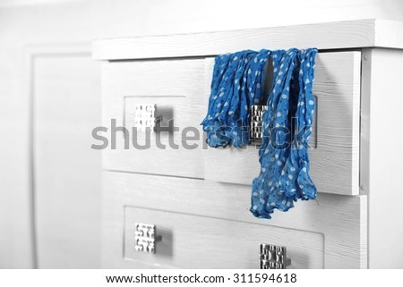 White wooden chest of drawer with scarf in opened drawer