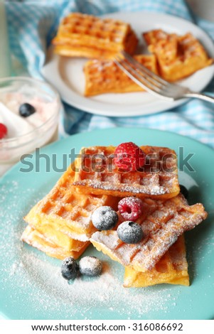 Sweet homemade waffles with forest berries on plate, on light background