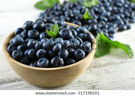 Tasty ripe blueberries with mint in bowl on table close up