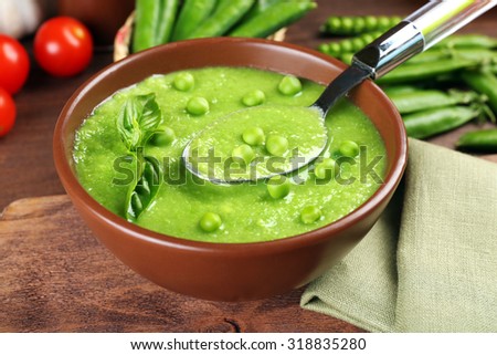 Tasty peas soup and cherry tomatoes on table close up
