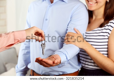 Real estate agent giving keys to young couple