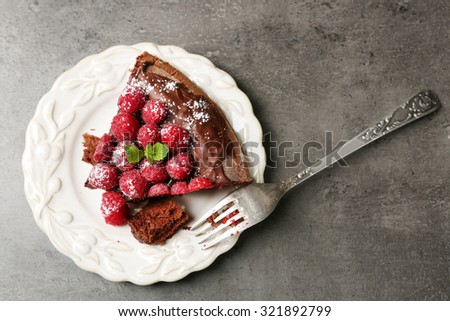 Piece of cake with Chocolate Glaze and raspberries on plate on dark background