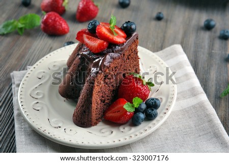 Piece of chocolate cake with berries in plate on table, closeup