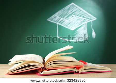 Open books and bachelor hat drawing on blackboard background