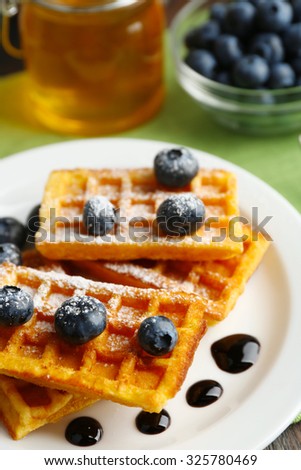 Sweet homemade waffles with forest berries and chocolate sauce on table background