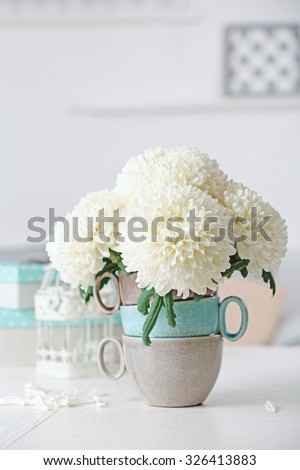 Beautiful flowers in vase on table in room on bright background