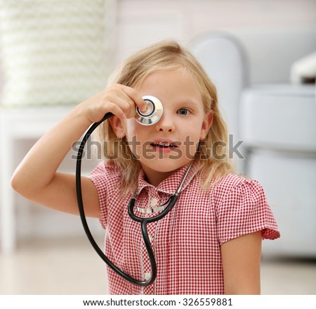 Little girl playing with stethoscope in the room