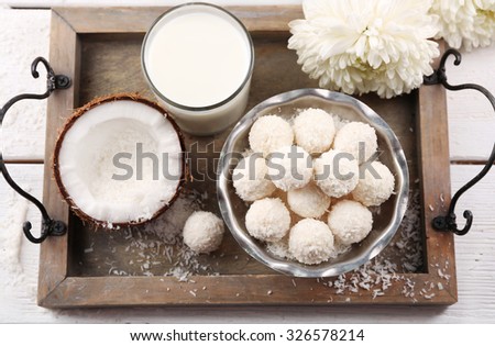 Homemade sweets in coconut flakes and fresh coconut on tray, close-up