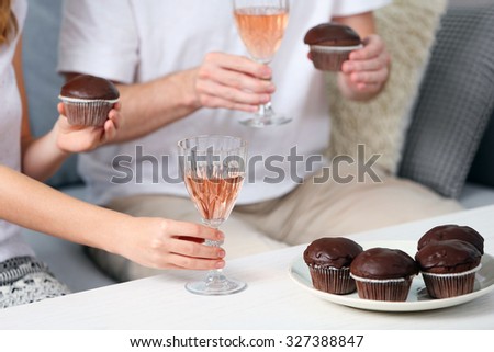 Friends hands with glasses of wine and desserts, close up