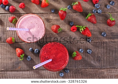 Glasses of berry smoothie on wooden table, top view