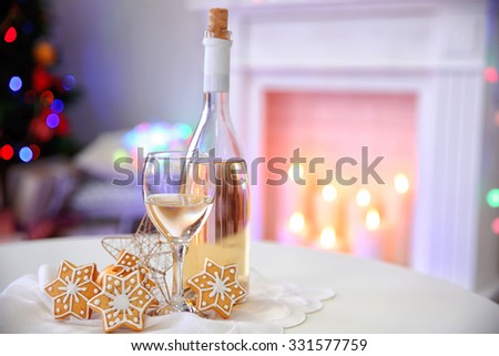 Bottle and glass of wine with Christmas decor against colorful bokeh lights background