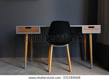 Black modern chair  and wooden table in the room, close up, back view