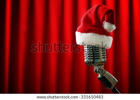 Vintage microphone with Christmas hat on red curtain background