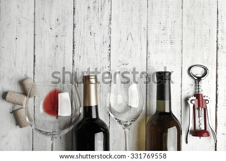 Bottles of wine, glass and corkscrew on wooden table,  black and white retro stylization