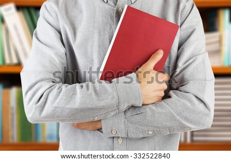 Male hands holding book on bookshelves background