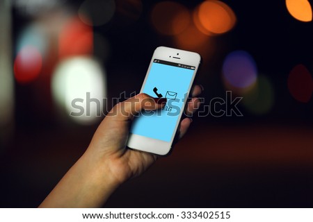 Female hand with mobile phone on blurred night lights background