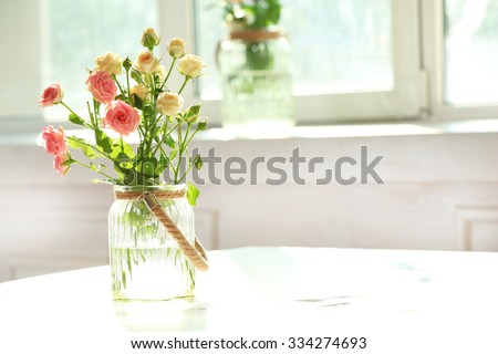 Beautiful spring flowers in vase on window background