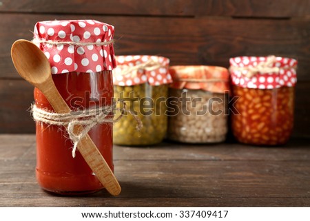 Glass jar of hot tomato sauce, on wooden background