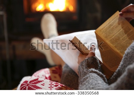Woman resting with book near fireplace