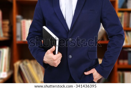 Male hand holding book on bookshelves background