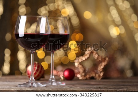 Red wine and Christmas ornaments on wooden table on golden background