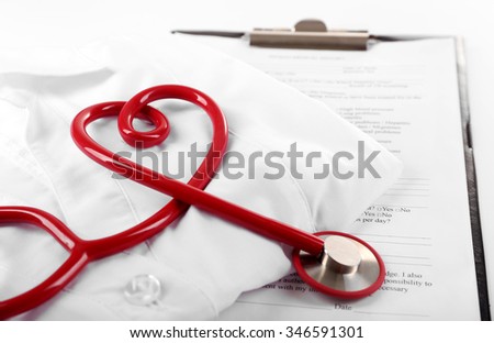 Red stethoscope, medical record and uniform on white background