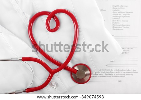 Red stethoscope, medical record and uniform, close up