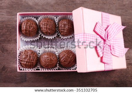 Tasty chocolate candies in pink gift box on wooden background, close up