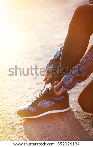 Woman in sportswear tying shoelaces on sneakers outdoor close-up