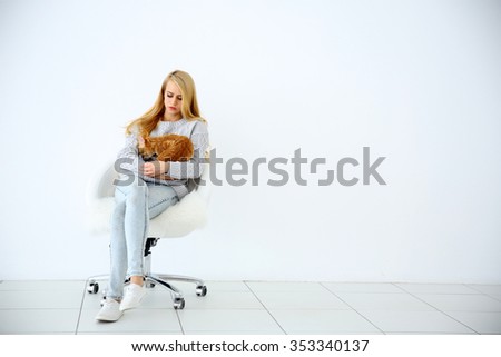 Young woman with red cat sitting on chair against white background