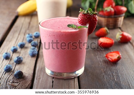 Glasses of fresh cold smoothie with fruit and berries, on wooden background