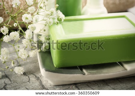 Soap on a dish with bottles over wooden background, close up