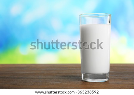 Glass of milk on table on blurred natural background