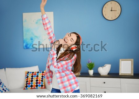 Crazy young woman with headphones listening to music and singing at home