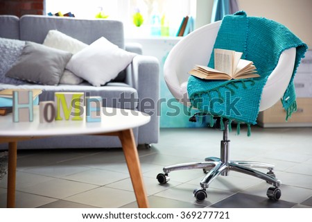 Modern living room interior in grey tones with bright blue plaid and book on chair