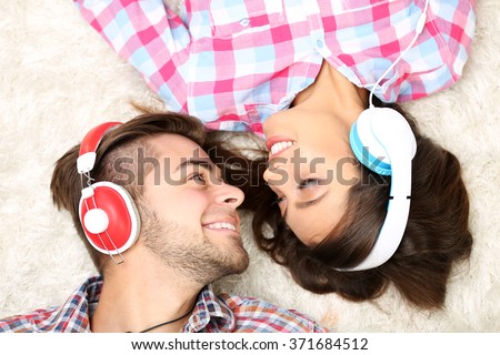 Teenager couple listening to music with headphones on a carpet