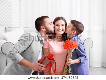 Husband and son giving gift box and roses to wife