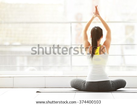 Health concept. Young attractive woman does yoga exercise in the gym  against window