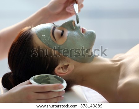 Spa concept. Young woman with nutrient facial mask in beauty salon, close up
